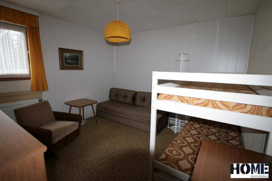 Schlafzimmer mit Etagenbett, Sofa und Fenster, ideal als Kinder- oder Gästezimmer.