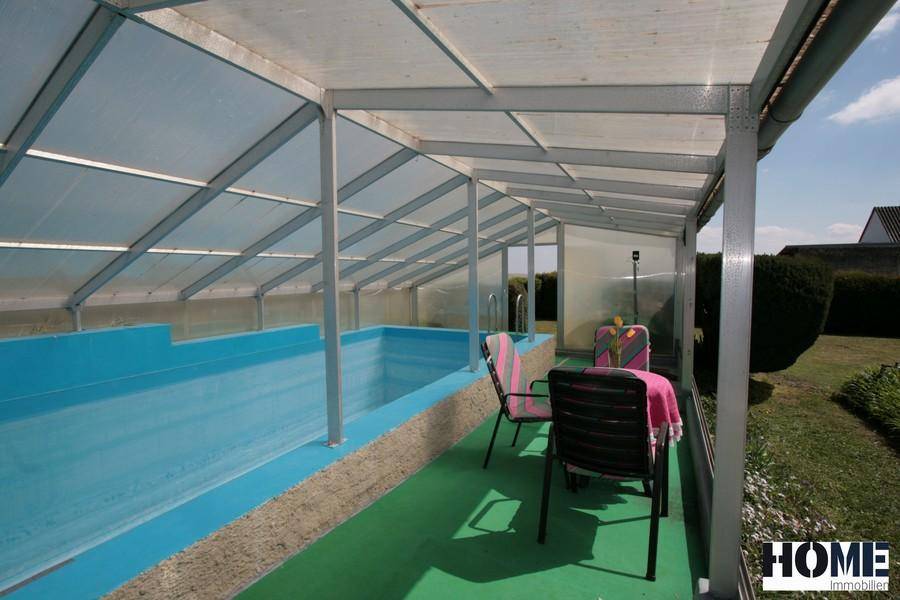 Überdachter Poolbereich mit Sitzgelegenheiten und Blick auf den umliegenden Garten.