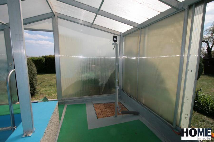 Duschbereich im überdachten Poolhaus mit Blick auf den Garten und viel Tageslicht.
