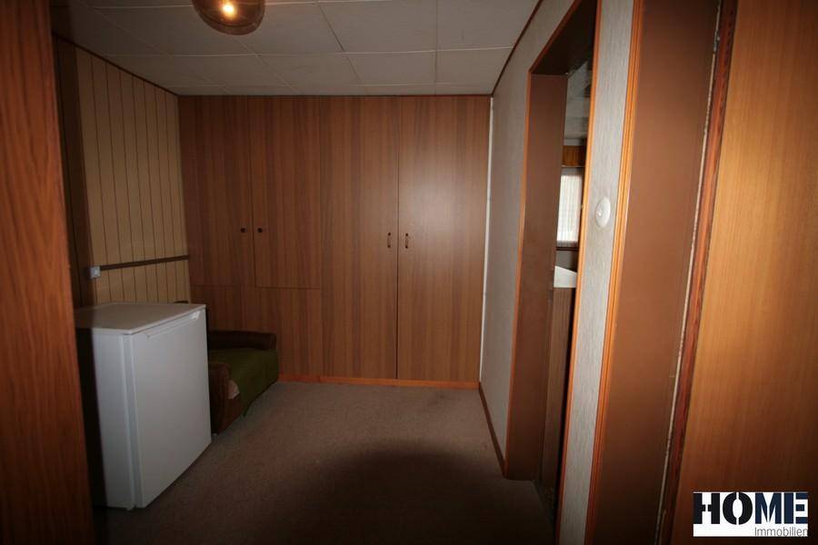 Praktischer Hauswirtschaftsraum mit Holzvertäfelung, Einbauschränken und zusätzlichem Kühlschrank.