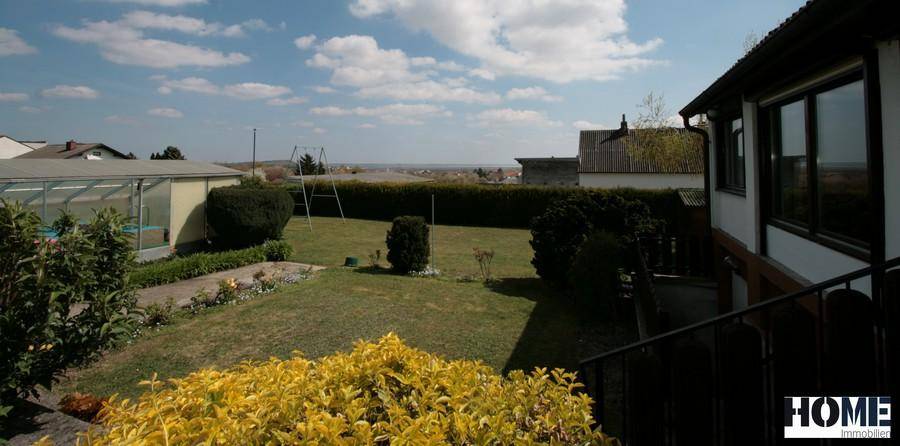 Gepflegter Gartenbereich mit Rasen, Sträuchern und Blick auf die Umgebung, angrenzend an das Haus.