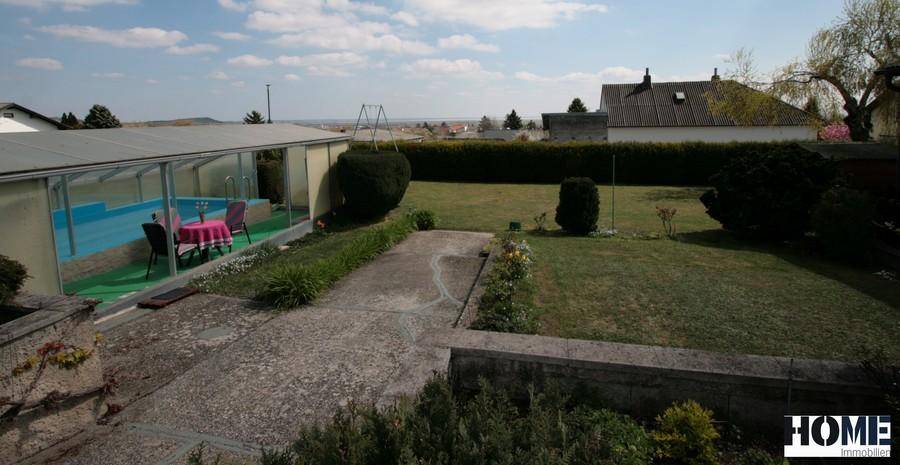 Großer Garten mit überdachtem Pool, Rasenfläche und weitem Blick in die Landschaft.