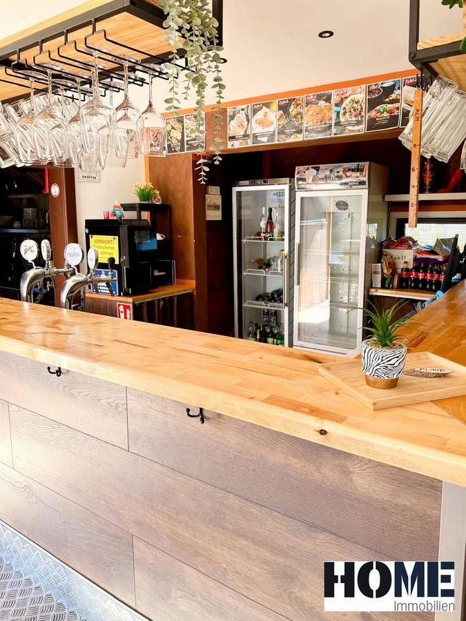 Thekenbereich mit Zapfanlage, Gläserhaltern und Kühlschränken, bereit für den Gastronomiebetrieb.