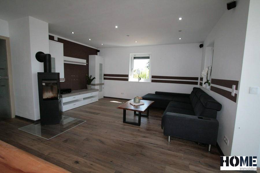 Gemütliches Wohnzimmer mit Holzboden, modernem Kaminofen und bequemer Sitzecke.