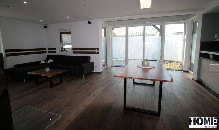 Offener Wohn- und Essbereich mit Holzboden, großem Esstisch und Zugang zur Terrasse.