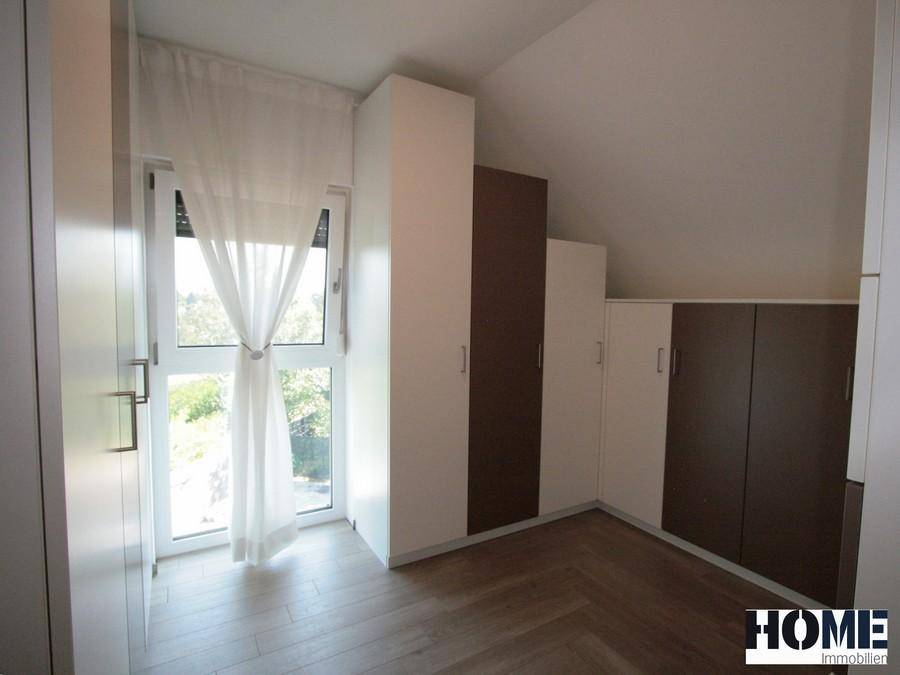 Schlafzimmer mit maßgefertigten Einbauschränken, Holzboden und Zugang nach draußen.