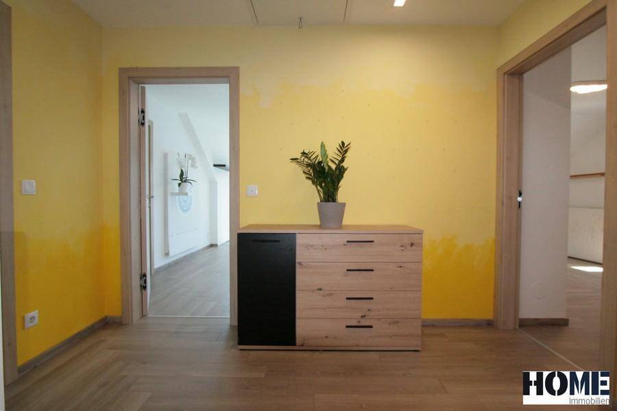 Heller Flur im Obergeschoss mit Holzboden, Kommode und gelb gestrichenen Wänden.