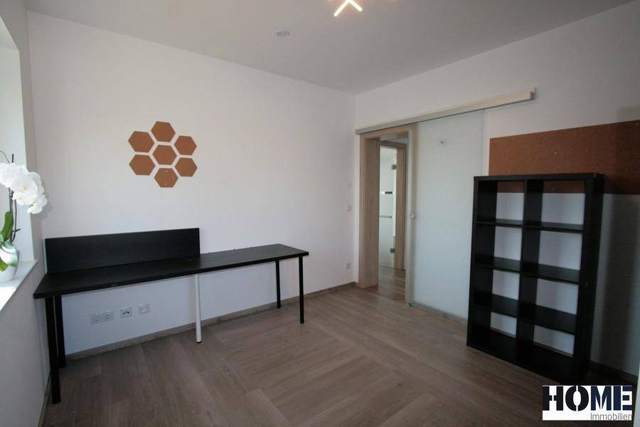 Modernes Arbeitszimmer mit Holzboden, Schreibtisch und Schiebetür zum Flur.