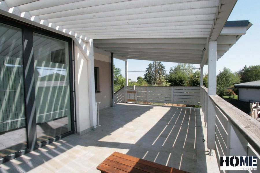 Weitläufige Terrasse mit Überdachung und Blick ins Grüne, perfekt für Outdoor-Living.