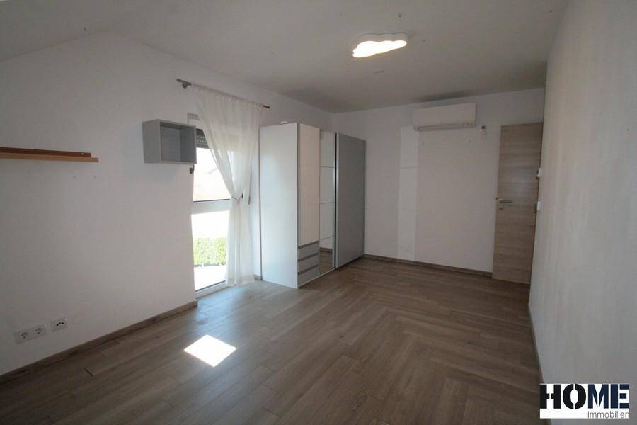 Helles Schlafzimmer mit Spiegelschrank, Klimaanlage und Holzboden.