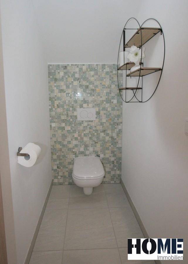 Modernes Gäste-WC mit Wand-WC und dekorativen Mosaikfliesen an der Wand.