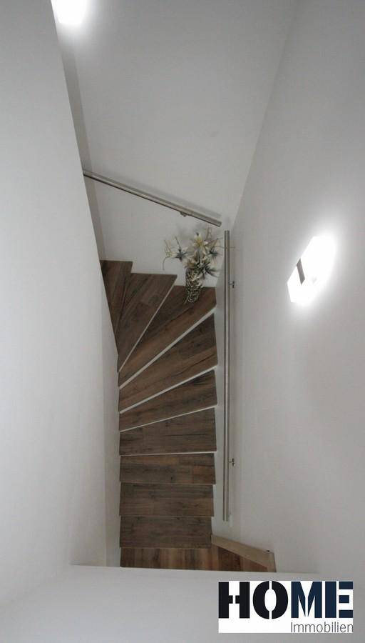 Elegante Holzwendeltreppe mit Edelstahlgeländer, die die Etagen verbindet.