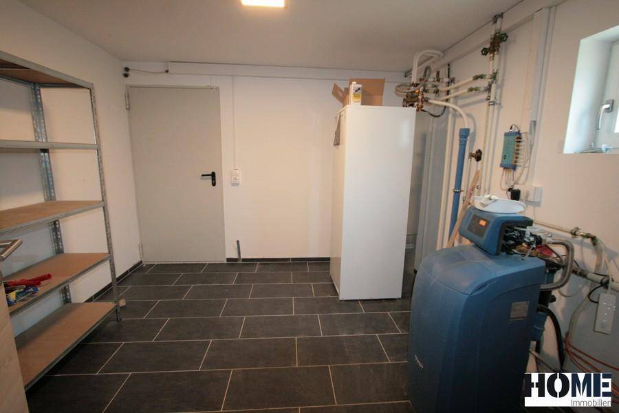 Hauswirtschaftsraum im Keller mit Wasserenthärtungsanlage, Regalen und Fliesenboden.