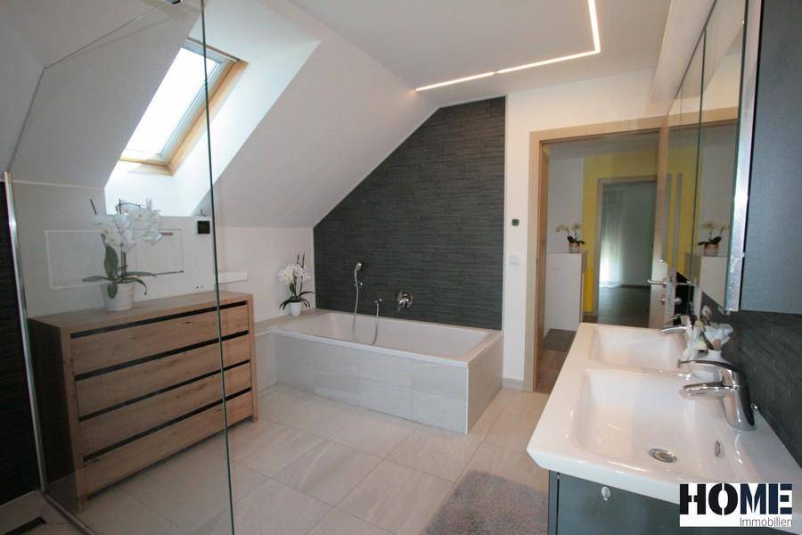 Geräumiges Badezimmer mit Badewanne, Holzkommode und Blick auf den Flur.