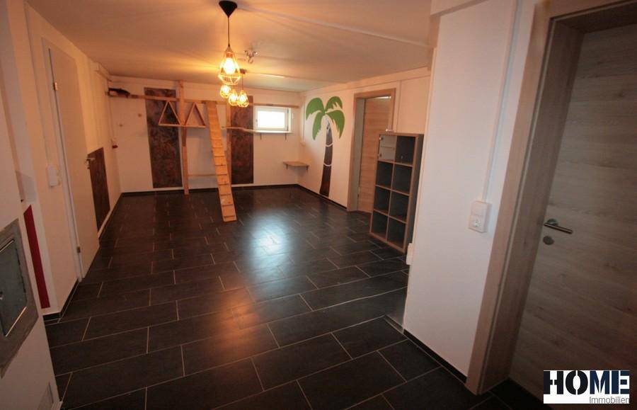 Geräumiger Kellerraum mit dunklem Fliesenboden und kreativer Wandgestaltung.