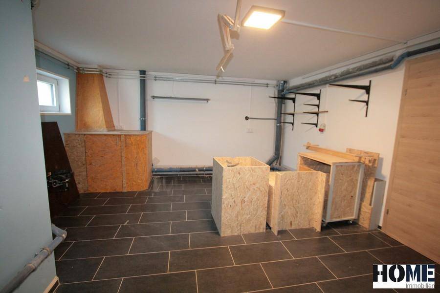 Unfertiger Kellerraum mit Fliesenboden, einem Fenster und sichtbaren Installationen.