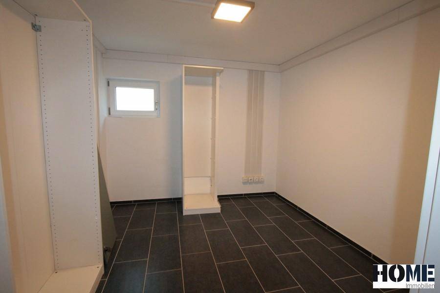 Kellerraum mit Fliesenboden und kleinem Fenster, ideal als Abstellraum.