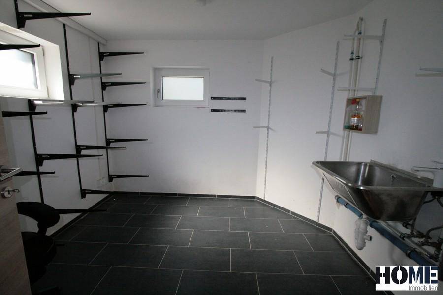 Praktischer Hauswirtschaftsraum im Keller mit Waschbecken und Regalsystemen.
