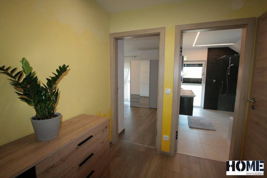 Flur mit gelben Wänden, Holzboden und Zugang zu Schlafzimmer und Bad.