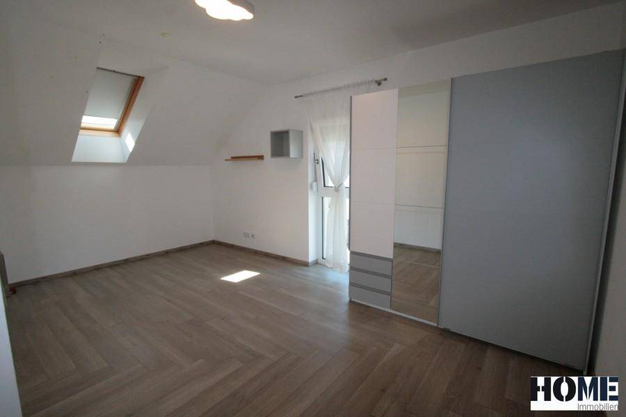 Schlafzimmer mit großem Spiegelschrank, Holzboden und Dachfenster.