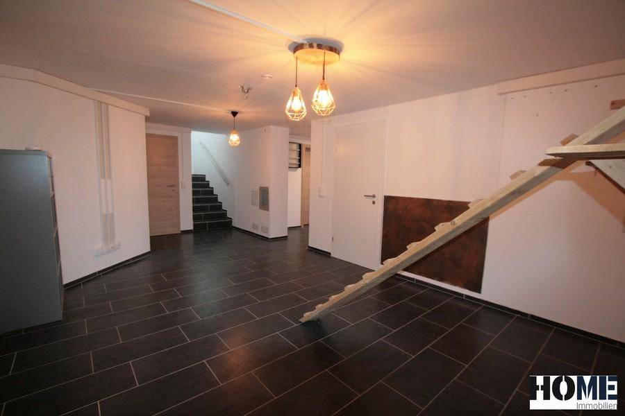 Großer Kellerraum mit Fliesenboden und Zugang zum Treppenhaus.