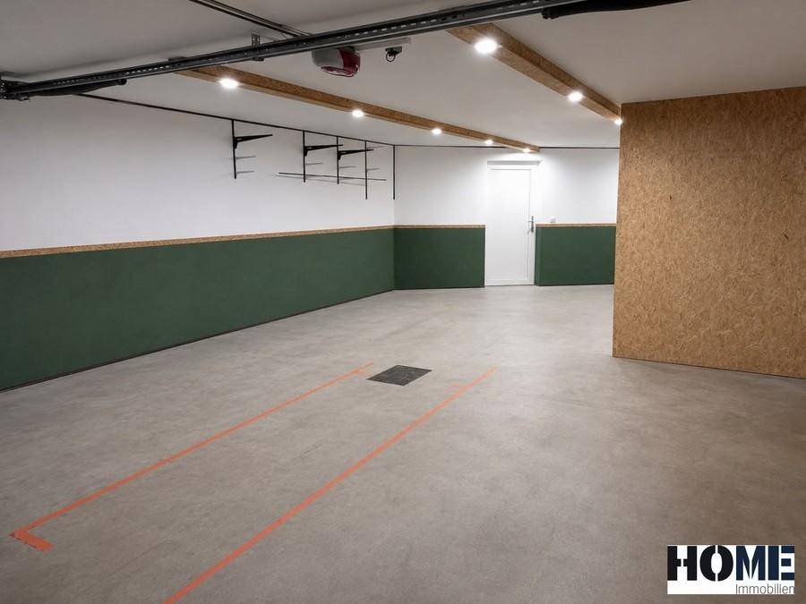Leere Garage mit Betonboden, Parkmarkierungen und einer Tür zum Innenbereich.