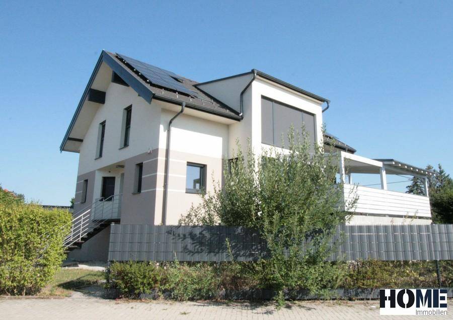 Modernes Einfamilienhaus mit Photovoltaikanlage auf dem Dach und gepflegtem Vorgarten.