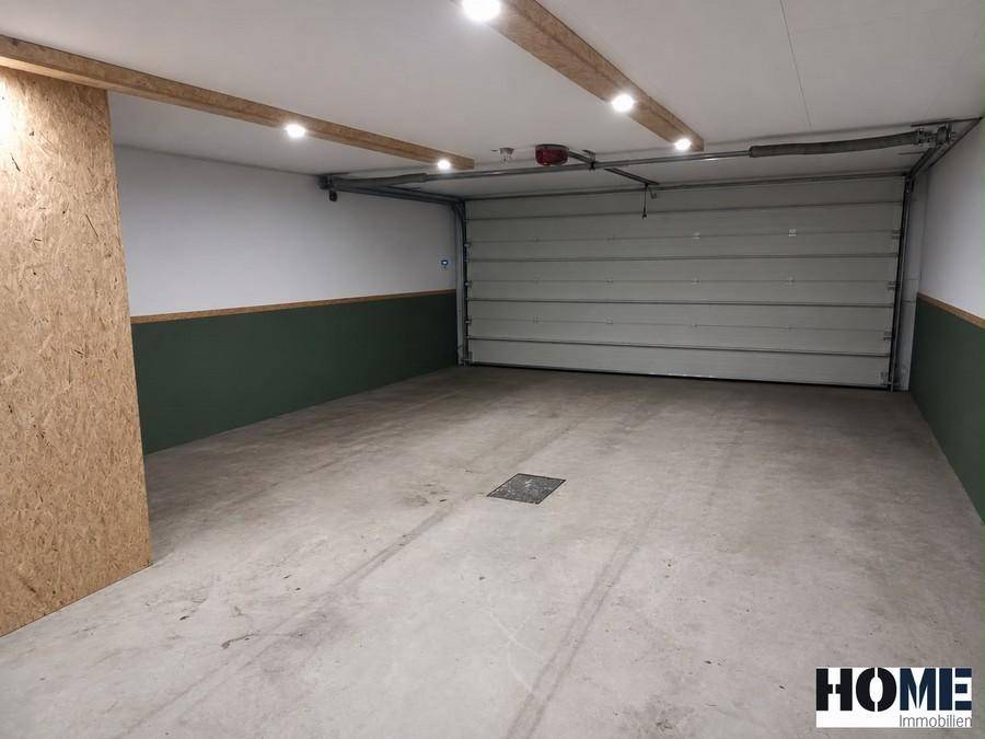 Geräumige Garage mit Betonboden, automatischem Tor und Deckenbeleuchtung.
