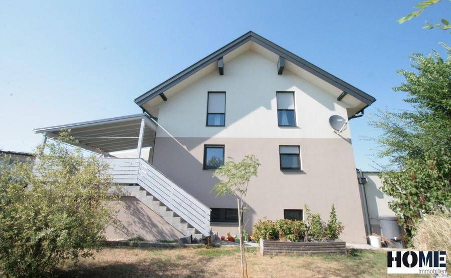 Rückansicht des Hauses mit überdachter Terrasse und Außentreppe im Gartenbereich.
