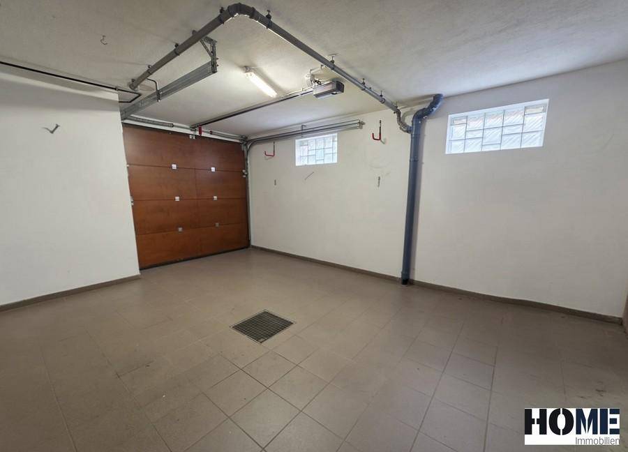 Geräumige Garage mit Fliesenboden, Sektionaltor und kleinen Fenstern für Tageslicht.