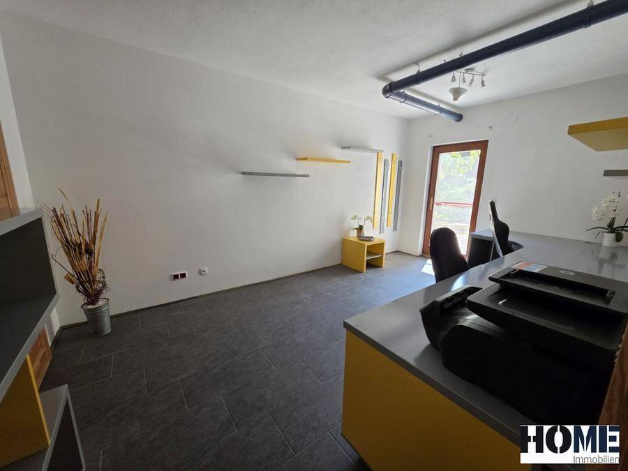 Helles Büro mit dunklen Fliesen, gelben Akzenten und Zugang zum Außenbereich.