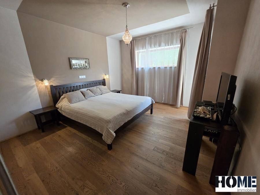 Geräumiges Schlafzimmer mit großem Doppelbett, Holzboden und einem Fenster, das Tageslicht hereinlässt.