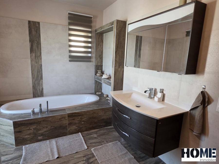 Badezimmer mit elegantem Waschtisch, Spiegelschrank und einer modernen Badewanne.
