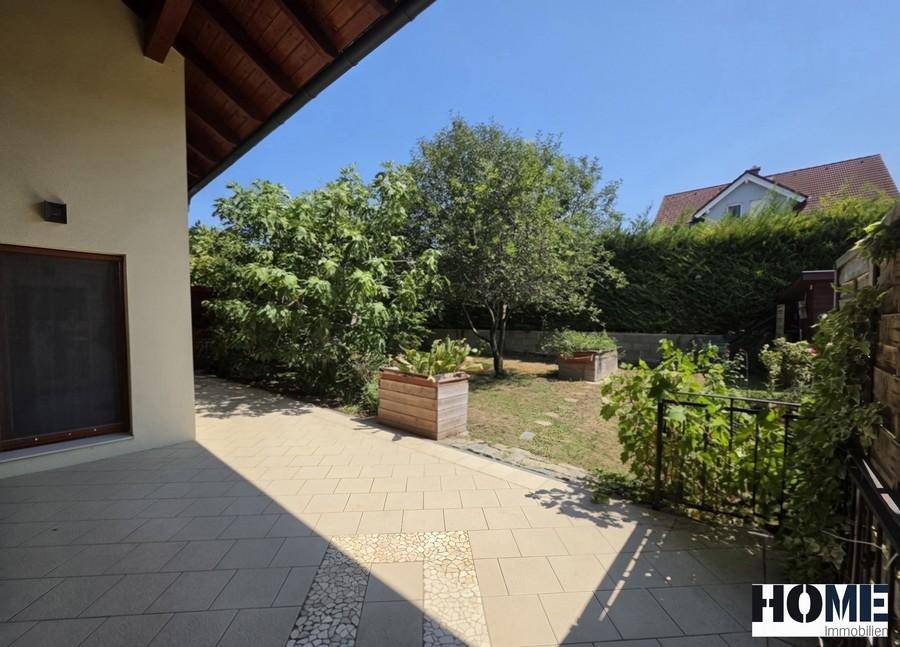 Grosse gepflasterte Terrasse mit Blick auf den Garten und die umliegende Natur.