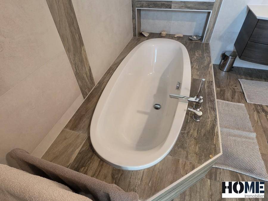 Detailansicht der modernen, ovalen Badewanne mit stilvollen Armaturen im Badezimmer.