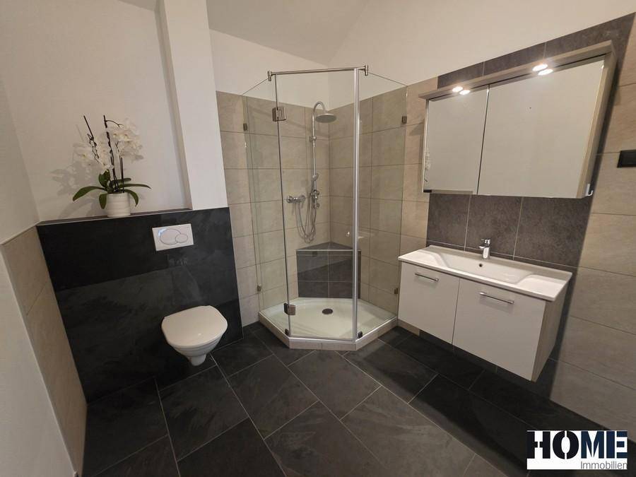 Helles Badezimmer mit moderner Duschkabine, Waschtisch und Spiegelschrank.