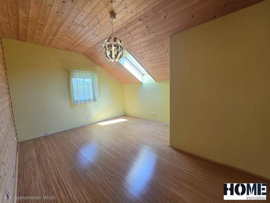 Helles Zimmer im Dachgeschoss mit Holzbalkendecke, Fenster und Laminatboden.