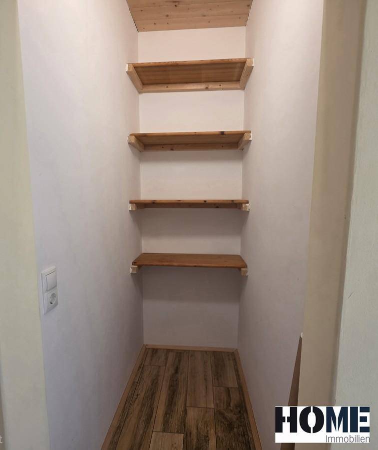Praktischer Abstellraum mit mehreren Holzregalen und Fliesenboden in Holzoptik.