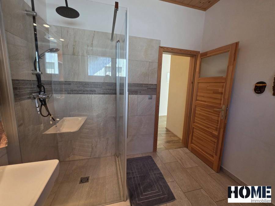 Geräumige Duschkabine mit Regendusche und Zugang zu einem weiteren Zimmer.