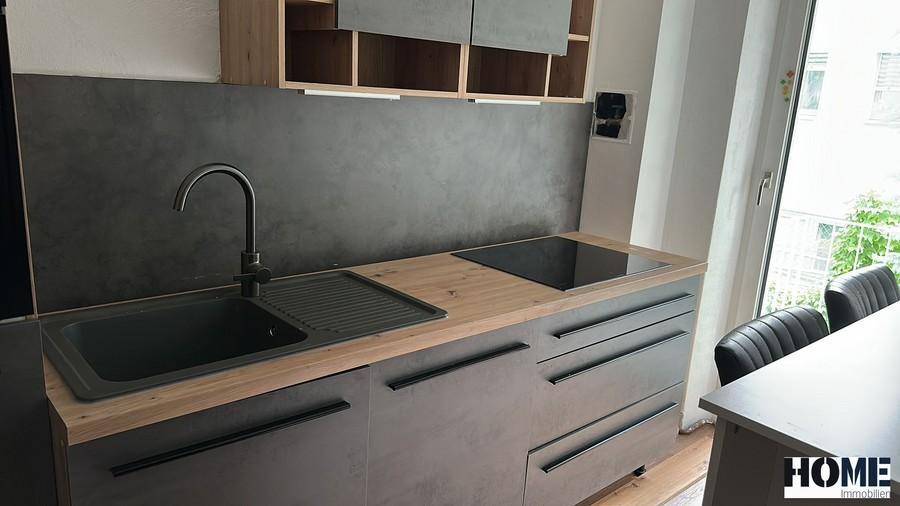 Moderne Küche mit Holz-Arbeitsplatte, dunkler Spüle und Induktionskochfeld, ausgestattet mit Einbauschränken.