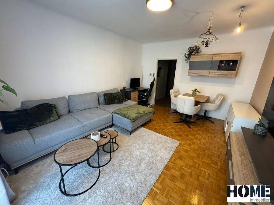 Heller Wohn-Essbereich mit gemütlichem Sofa, Couchtisch und einem Esstisch mit Stühlen.