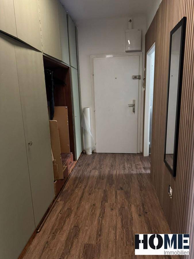 Eingangsbereich mit Garderobenschrank, Spiegel und Holzboden, bietet praktischen Stauraum.