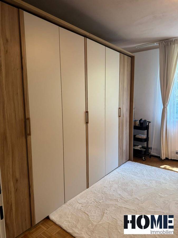 Großer Einbauschrank mit hellen Fronten und Holzrahmen, bietet viel Stauraum im Schlafzimmer.