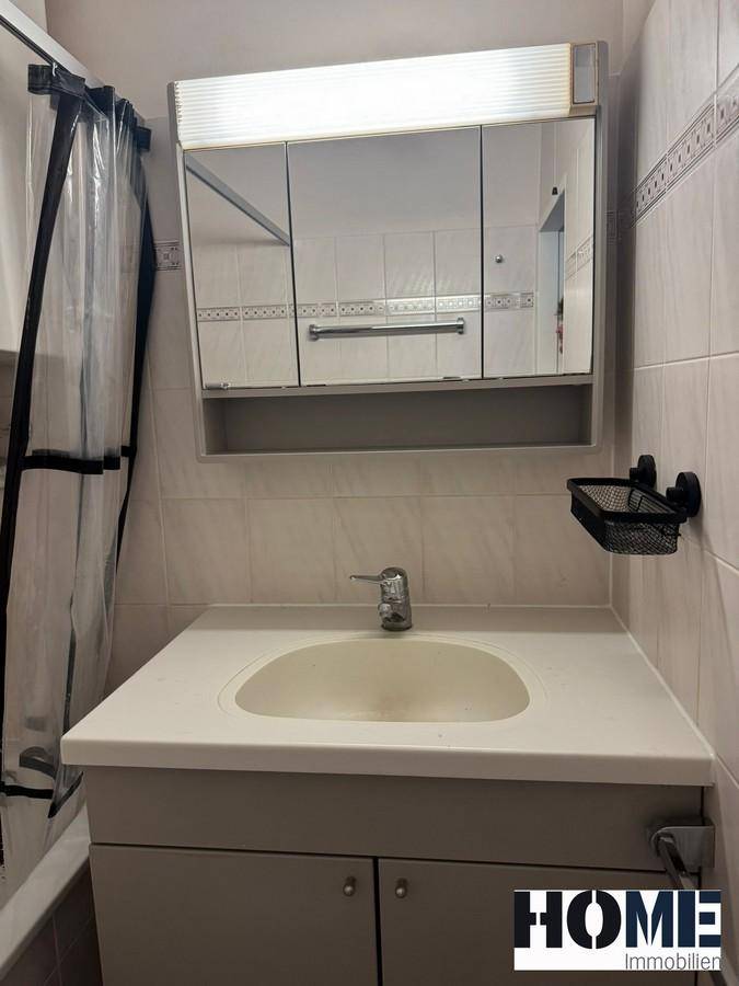 Waschbecken mit Unterschrank und einem Spiegelschrank mit integrierter Beleuchtung im Badezimmer.