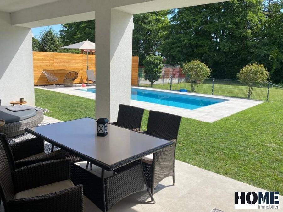 Gemütliche Terrasse mit Esstisch und Lounge-Möbeln, direkt am Pool gelegen.