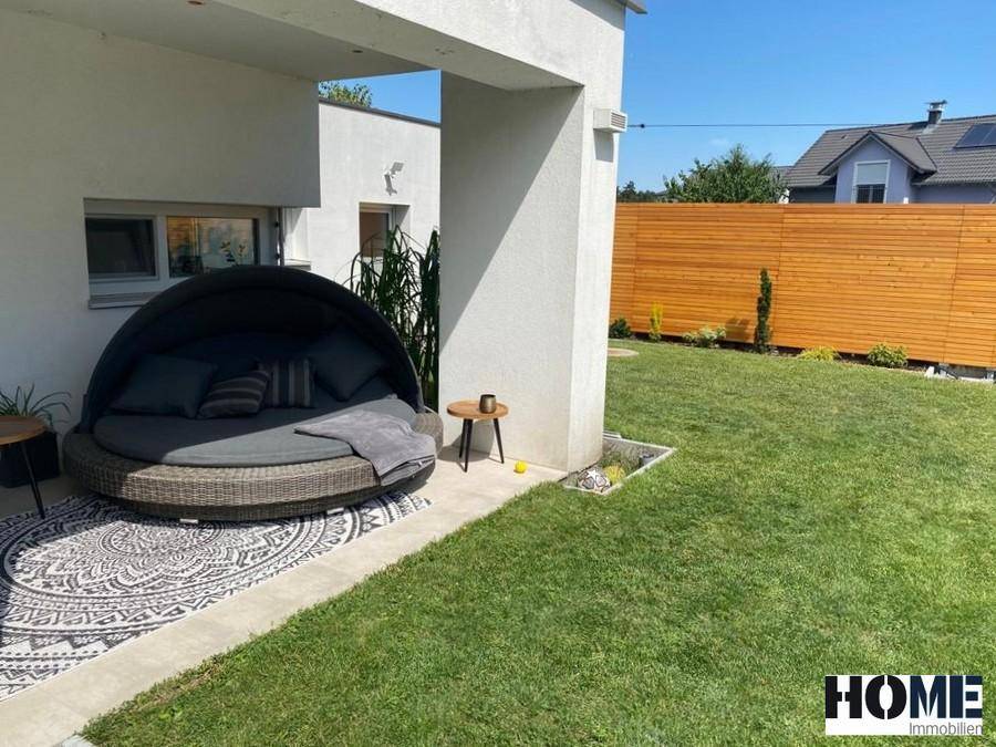 Gemütlicher Lounge-Bereich auf der Terrasse mit großem Tagesbett und Blick in den Garten.