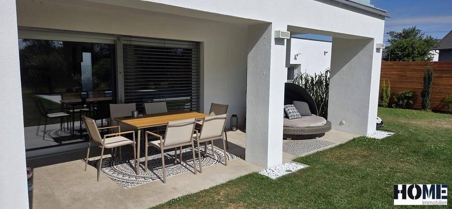 Überdachte Terrasse mit modernem Esstisch und Stühlen, ideal für Mahlzeiten im Freien.