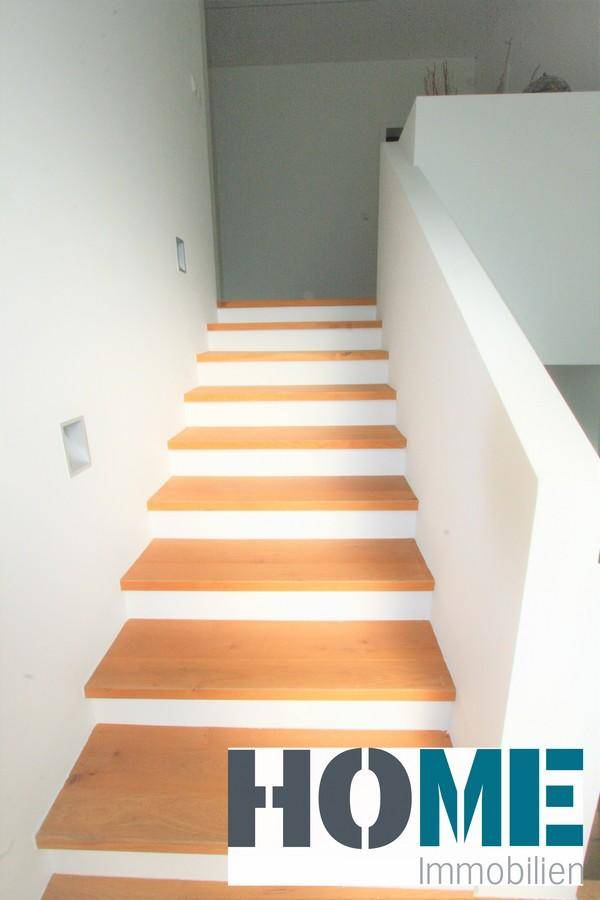 Moderne Holztreppe mit weißer Wand und minimalistischem Design.