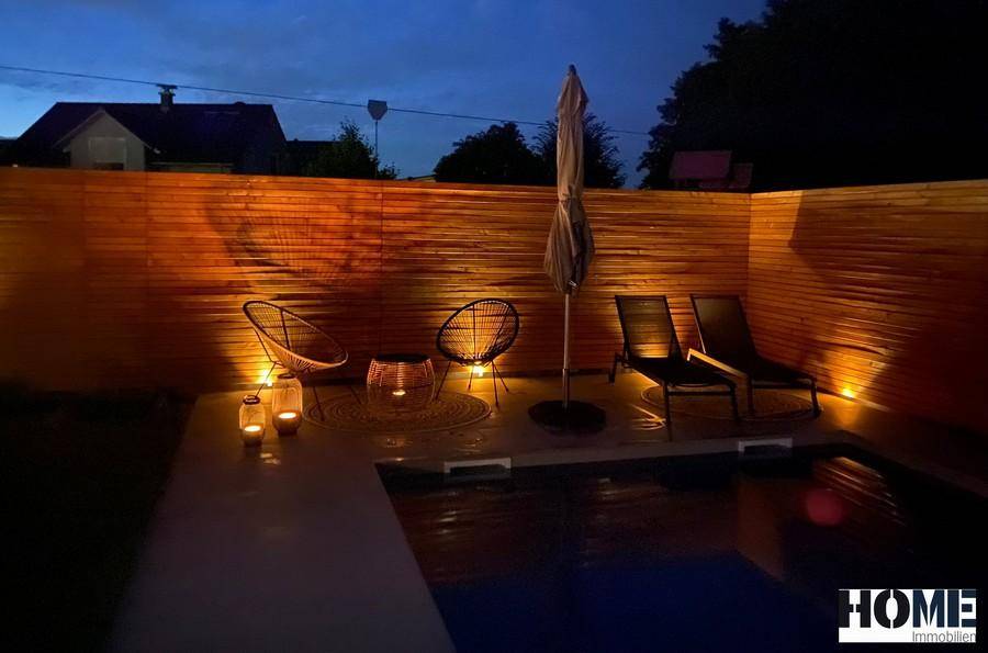 Stimmungsvoll beleuchteter Poolbereich bei Nacht mit Lounge-Möbeln und Kerzenlicht.