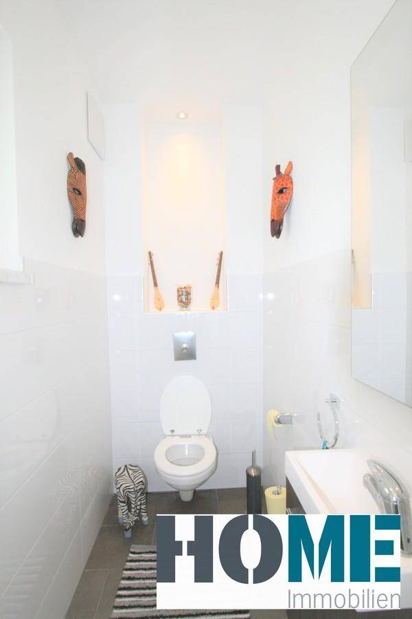 Modernes Gäste-WC mit Wand-WC, Waschbecken und dekorativen Wandelementen.